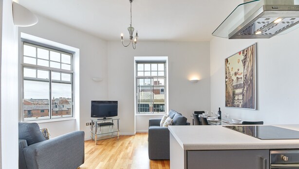 A modern living room with a sofa, a TV, and a dining area with a table and chairs. - The Loft in Newcastle Upon Tyne (Newcastle-upon-Tyne)