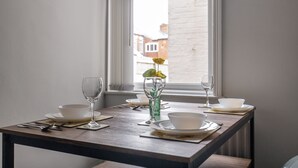A dining table set with white bowls, plates, and cutlery, positioned near a window with a view of buildings. - Mowbray in South Shields (South Shields)