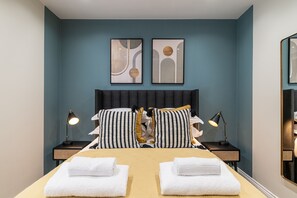 Une chambre d’hôtel comprenant un lit, deux tables de chevet, deux lampes et deux serviettes.