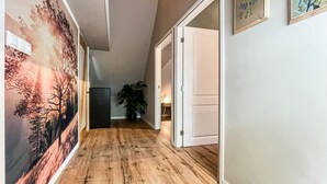 A hallway with wooden flooring, a refrigerator, a potted plant, and a door leading to another room. - Cozy home in Harich with WiFi (Harich)