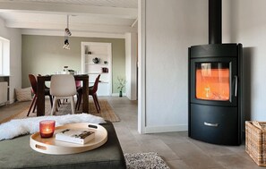 A cozy living room with a modern fireplace, a dining area with chairs and a table, and a bookshelf.