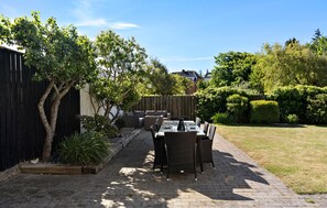 An outdoor patio with a table and chairs, surrounded by a wooden fence and lush greenery. - Nice home in Løgstør with WiFi (Løgstør)