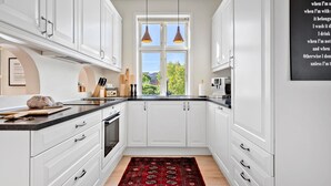 A modern kitchen with white cabinets, a black countertop, and a red patterned rug. - Nice home in Løgstør with WiFi (Løgstør)