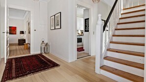 A spacious hallway with a wooden staircase, a red rug, and a kitchen visible in the background. - Nice home in Løgstør with WiFi (Løgstør)