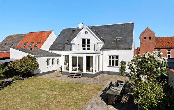 A two-story house with a large front porch, a covered patio, and a brick tower in the background. - Nice home in Løgstør with WiFi (Løgstør)