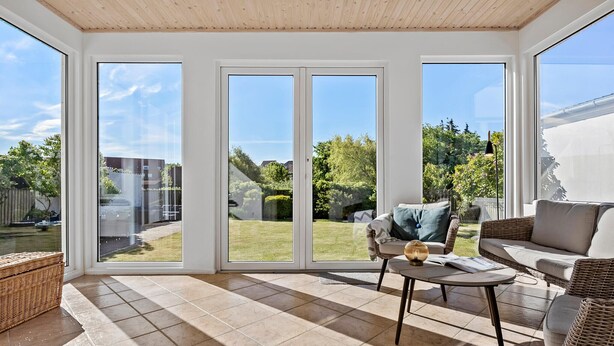 A sunlit room with large sliding glass doors, wicker furniture, and a tiled floor. - Nice home in Løgstør with WiFi (Løgstør)