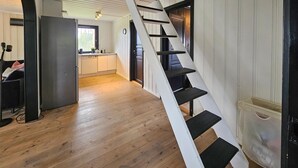Une cuisine moderne avec des meubles blancs, un réfrigérateur noir et une fenêtre donnant sur un paysage verdoyant.
