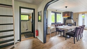 Un coin repas avec une table et des chaises en bois, une cheminée et une vue sur la verdure environnante.