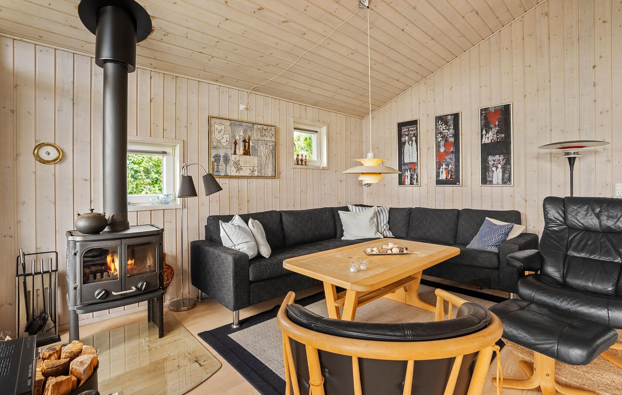 A cozy living room with a wood-burning stove, a sofa, a coffee table, and a leather armchair.