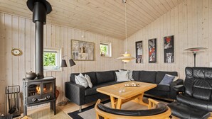 A cozy living room with a wood-burning stove, a sofa, a coffee table, and a leather armchair.