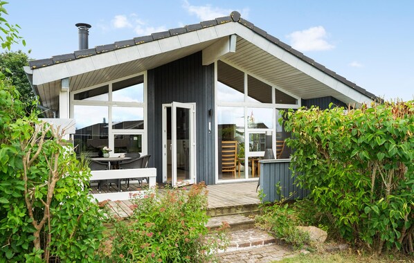 A modern house with a large deck, a chimney, and a garden with various plants.