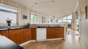 A modern kitchen with wooden cabinets, a dishwasher, and a large window offering a view of the outdoors.