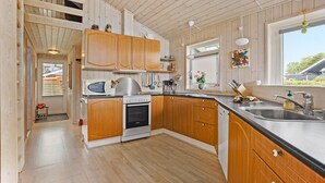 A compact kitchen with wooden cabinets, a stove, and a sink.