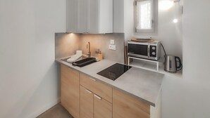 Een moderne keuken met een inbouwmagnetron, waterkoker en een klein raam boven de gootsteen.