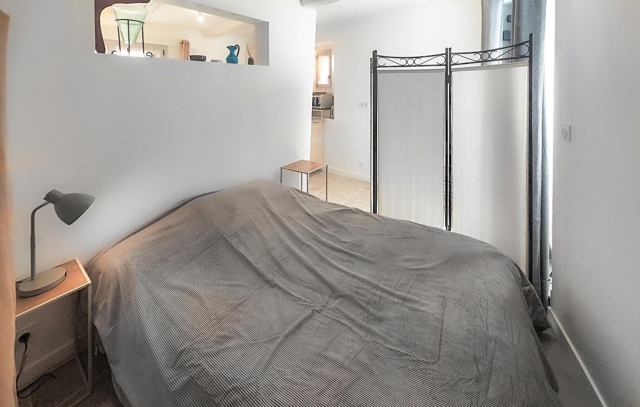 Una camera da letto con un letto, un comodino con una lampada, un tavolino con una tazza e una finestra con tende.