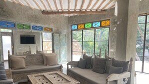 A spacious living room with a large window, a fireplace, and a coffee table. - Tulua House on Galu Beach: Private Villa @ Tamani (Diani)