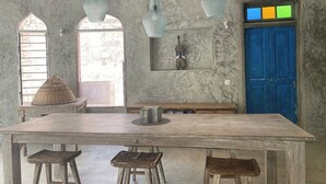 A rustic interior with a large wooden table, hanging light fixtures, and a blue door. - Tulua House on Galu Beach: Private Villa @ Tamani (Diani)