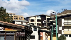 A multi-story building with a sign for 'Pain Artisanale' and a 'SUPERMARCHE' store. - Apartamento en les Deux Alpes (Les Deux Alpes)