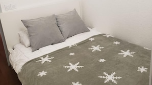 A bed with a grey blanket and pillows, a white headboard, and a white wall. - Apartamento en les Deux Alpes (Les Deux Alpes)