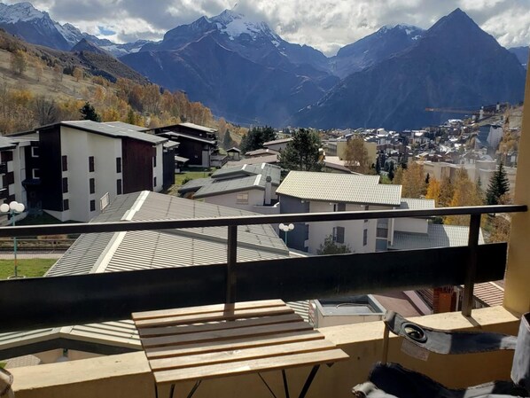 A residential area with modern buildings, a balcony with a view of mountains, and a clear sky.