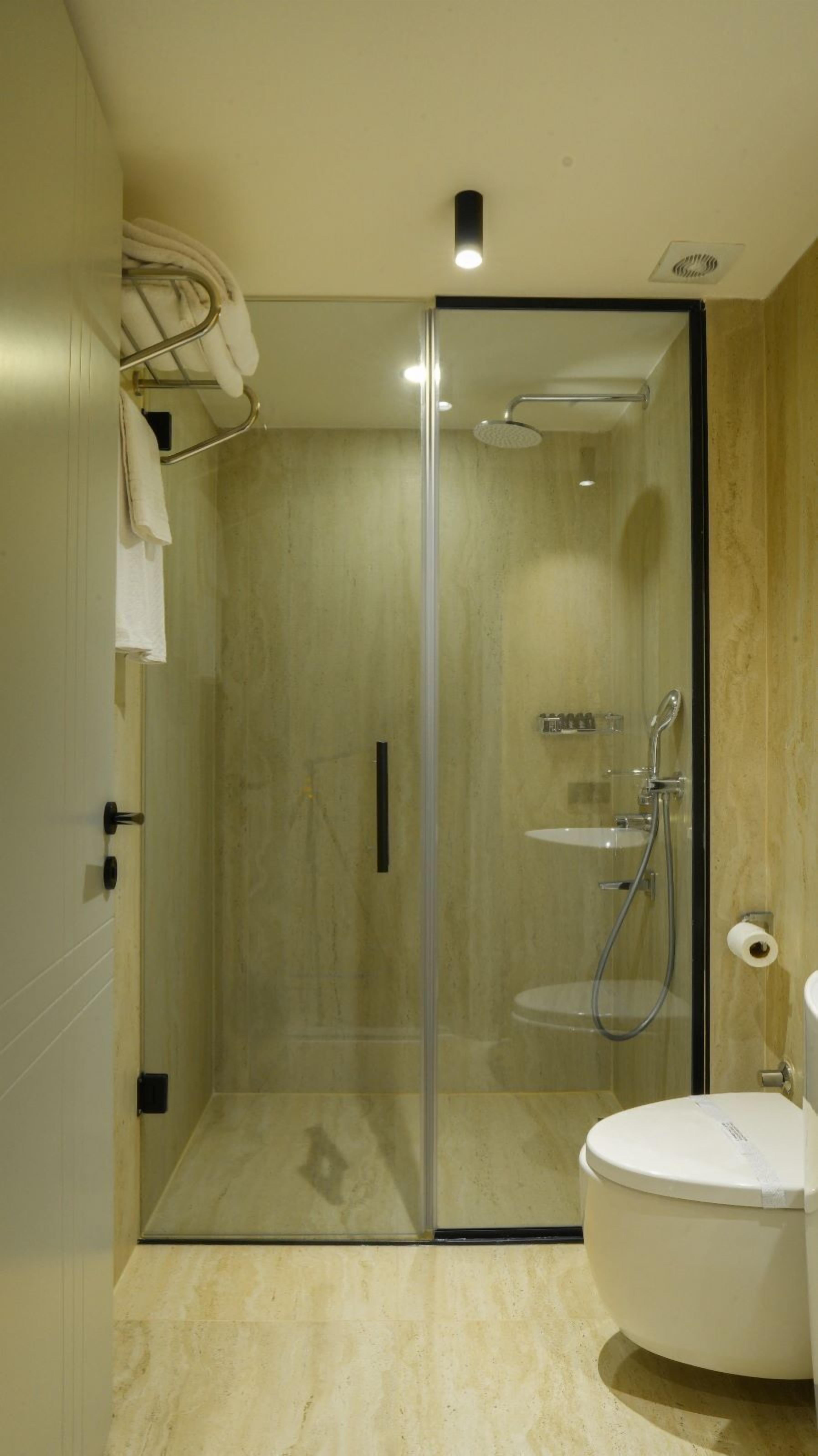 A modern bathroom with a glass-enclosed shower, a toilet, and a sink.
