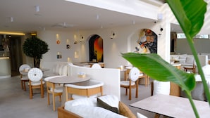 Um hall de hotel moderno com área de estar, uma grande árvore e um mural na parede.