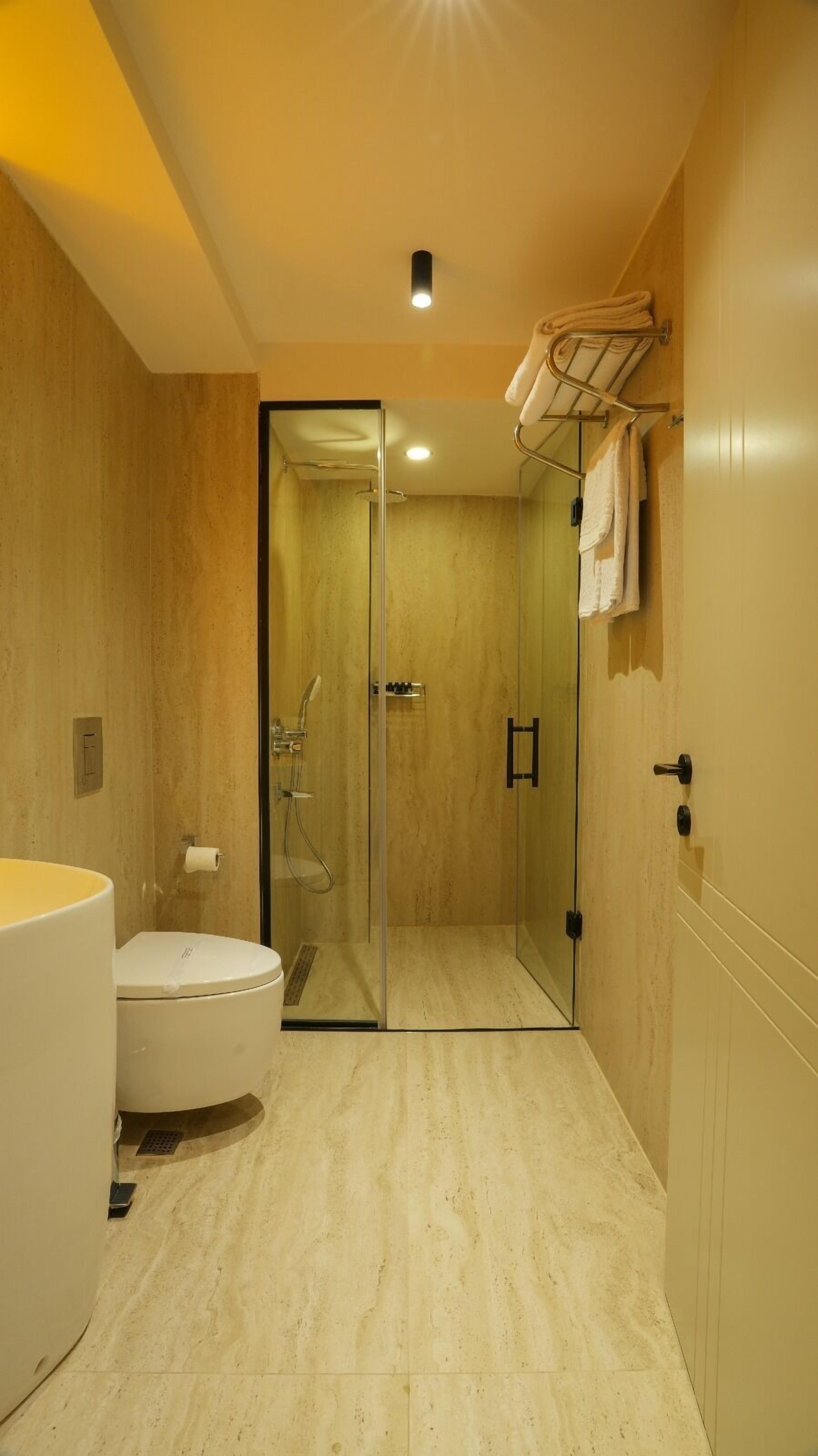 Un baño moderno con ducha de vidrio, inodoro y barra para toallas.