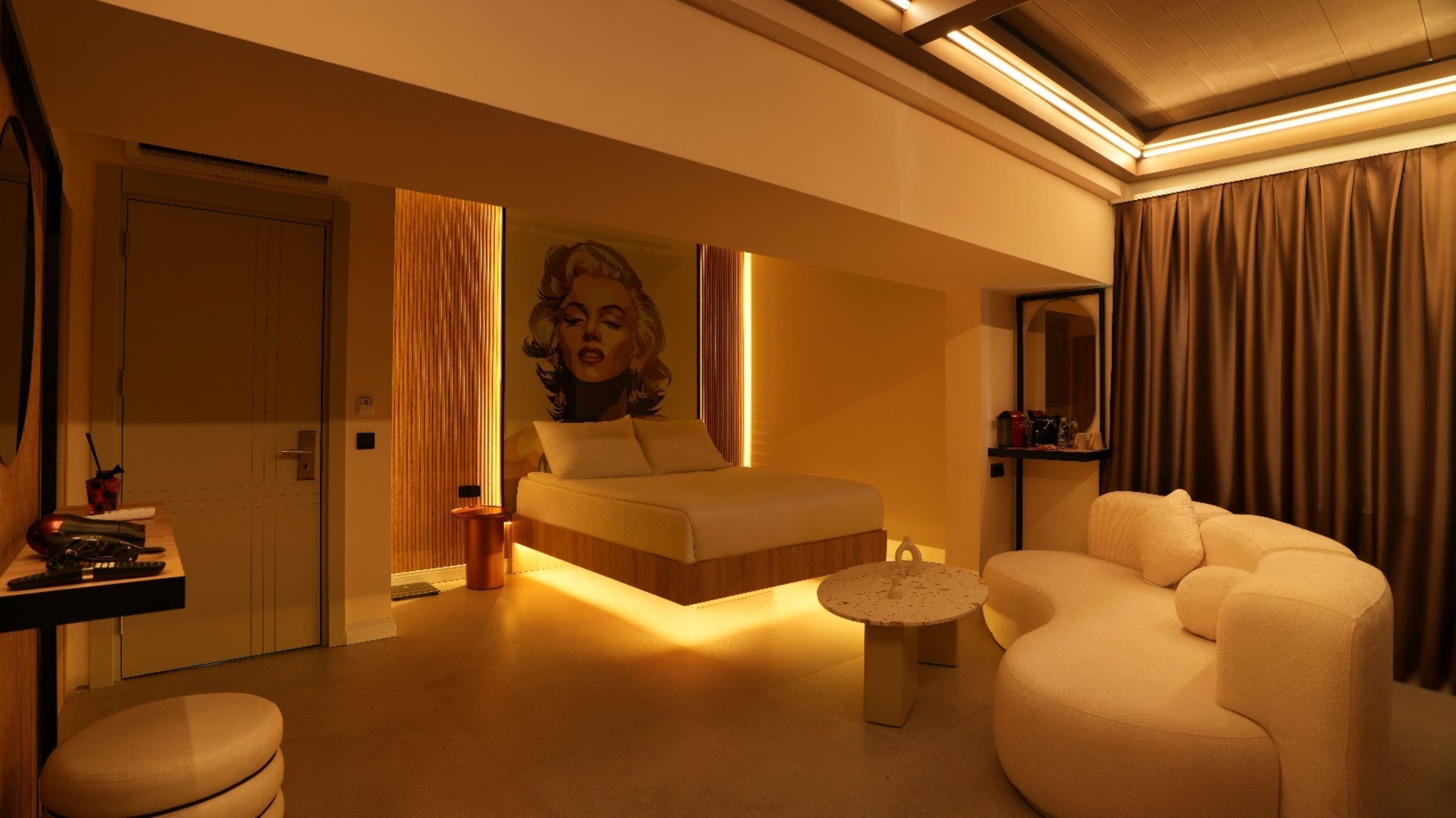 Une chambre d’hôtel moderne comprenant un lit, un coin salon, une petite table et un miroir.