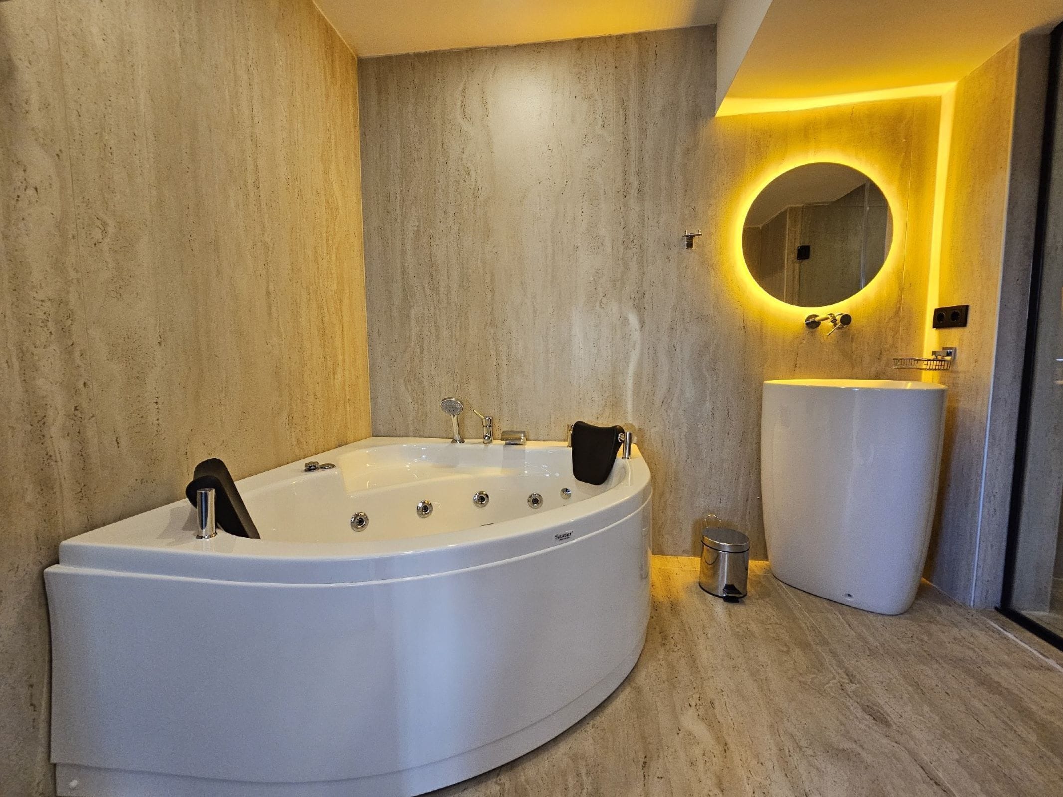 A modern bathroom with a freestanding bathtub, a round mirror with a yellow light, and a white sink.