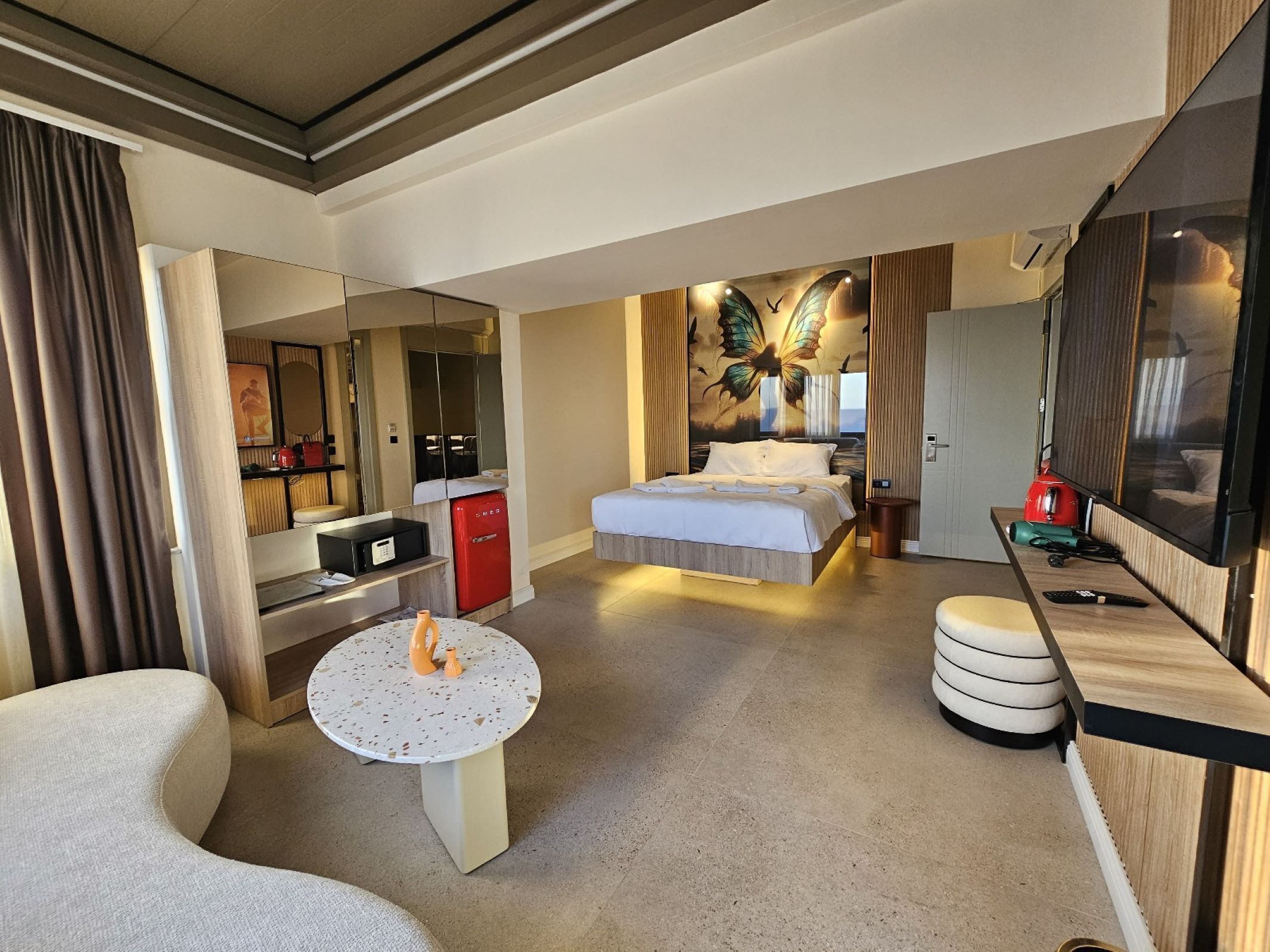 A hotel room with a bed, a desk, a TV, a minibar, and a bathroom.