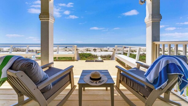 A wooden deck with two lounge chairs and a table, overlooking a beach with a clear view of the ocean and sandy shore. - Perfect Timing- On The Beach, Sleeps 10 (Port St. Joe)