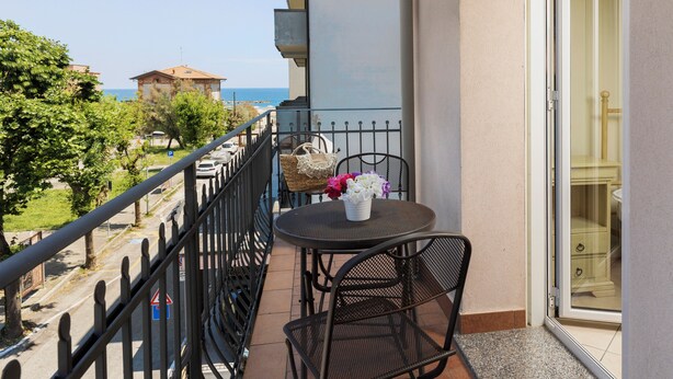 Un balcon avec une table et des chaises, une vue sur la mer et un bâtiment en arrière-plan.