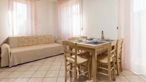 Une pièce comprenant une table à manger en bois, quatre chaises, un canapé beige et un petit objet décoratif posé sur la table.