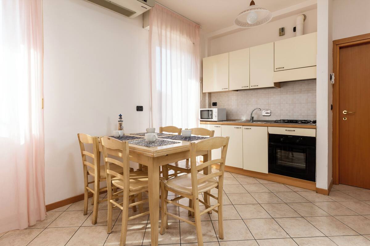 Une cuisine compacte comprenant une table à manger, des chaises, un four à micro-ondes, une cuisinière et des placards.
