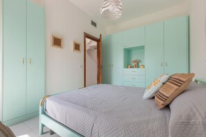 Um quarto com uma cama, um guarda-roupa e um pequeno armário.