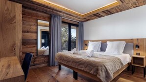 Un dormitorio moderno con techo de madera, una cama grande, un escritorio y una ventana con cortinas.