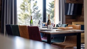 Una mesa de comedor con sillas, una botella de champán y copas.