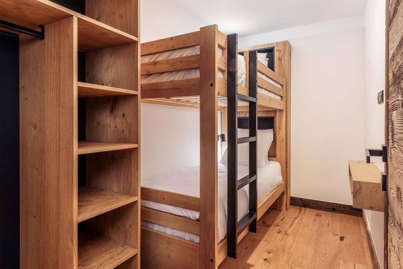 Una habitación compacta con una cama litera, estantes empotrados y un pequeño escritorio.