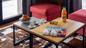 A cozy room with a wooden table, a bowl of croissants, a bottle of orange juice, and a pair of sunglasses.