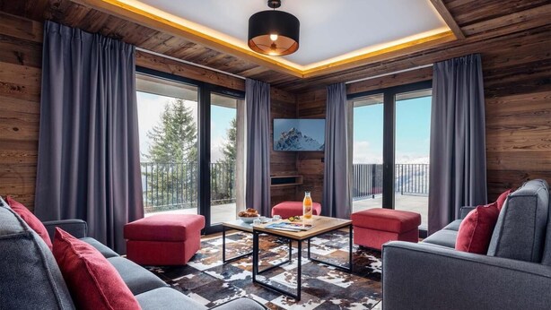 A modern living room with a fireplace, large windows, and a view of the outdoors.