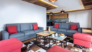 A modern living room with grey sofas, red cushions, a wooden coffee table, and a cowhide rug.