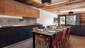 A modern kitchen with dark cabinets, a wooden dining table, and chairs.