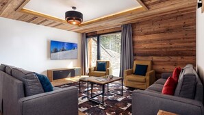 A modern living room with a wooden ceiling, a large window with curtains, and a cowhide rug.