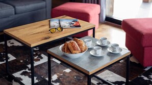 Una sala de estar acogedora con una mesa de centro de madera, un bol de pasteles y tazas blancas sobre una mesa a juego.