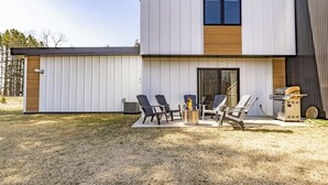 Uma casa moderna de dois andares com um pátio, área de estar externa e churrasqueira.