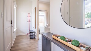 A hallway with a wooden floor, a coat rack, a bench, and a decorative tray with green balls and pine cones. - Spacious 3-bedroom house in Central Lubbock (Lubbock)