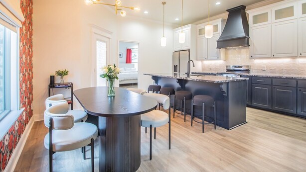 A modern kitchen with a central island, bar stools, pendant lighting, and a large stove. - Spacious 3-bedroom house in Central Lubbock (Lubbock)