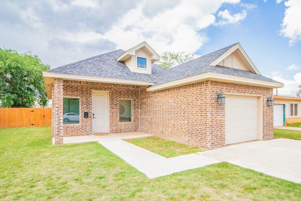 A single-story brick house with a garage, a small attached garage, and a front yard.