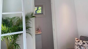 A room with a loft bed, a small window, a sink, and a plant.
