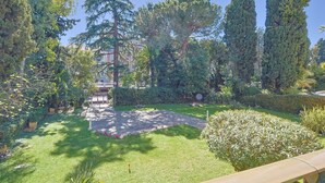 A well-maintained garden with a variety of trees, a paved pathway, and neatly trimmed hedges. - 217 Le Jungle in Cannes (Cannes)